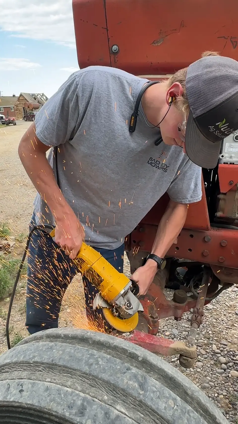 Preparing metal on a red tractor with an angle grinder